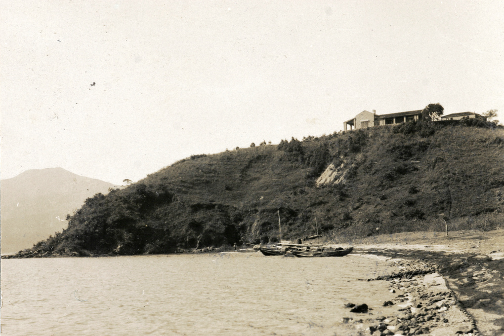 View of bungalow from shore with moored boats