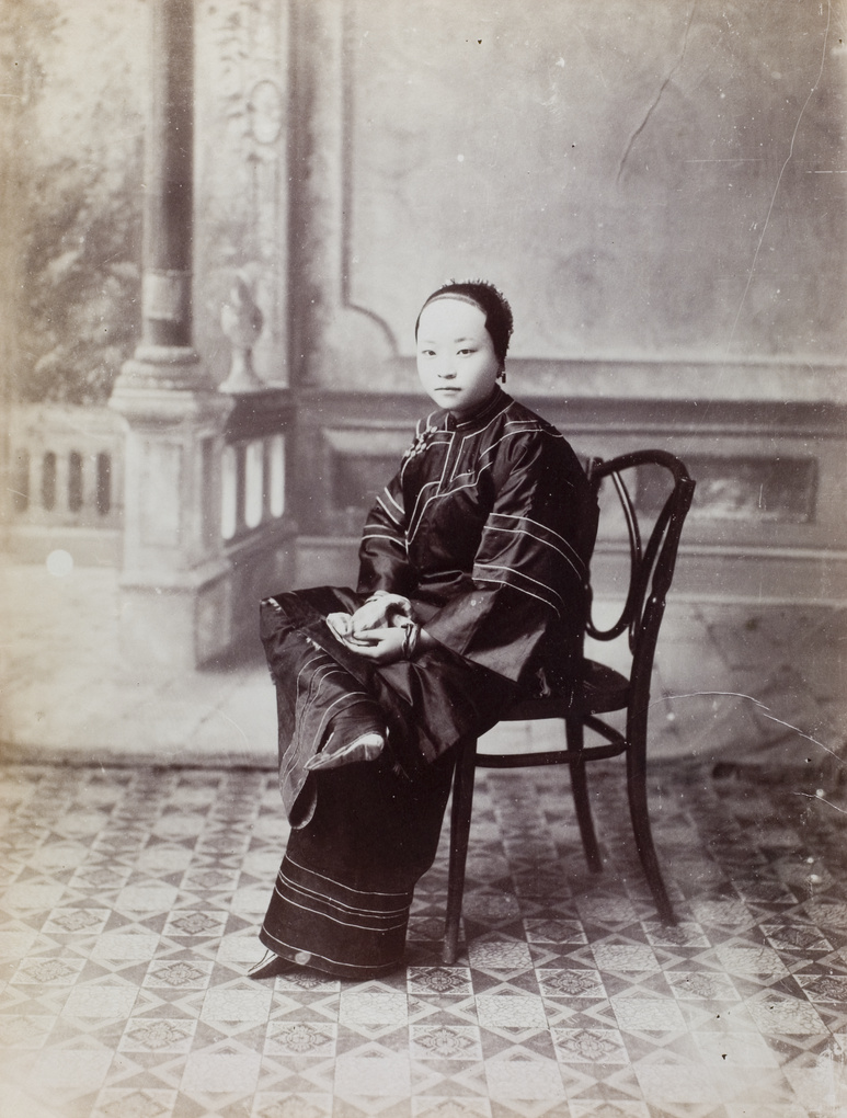 A woman with bound feet, in a photographer’s studio