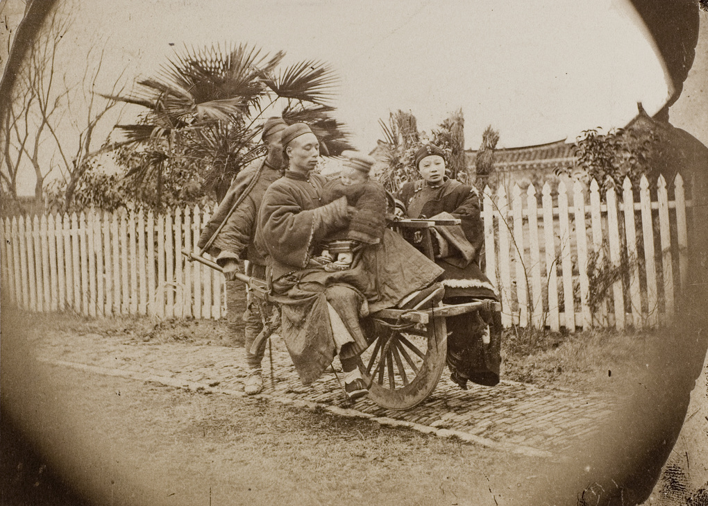 A man, a woman and a baby on a wheelbarrow