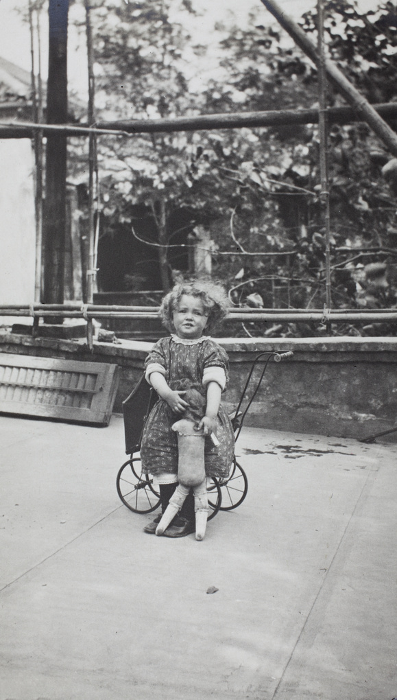 Mamie (Mary Chappel) with a doll and toy pram, 33 Victoria Road, Tianjin