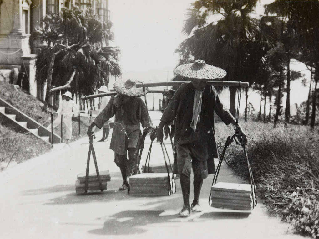 Two porters carrying construction materials