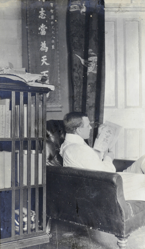 Hedgeland reading a Chinese publication in his sitting room, Tientsin