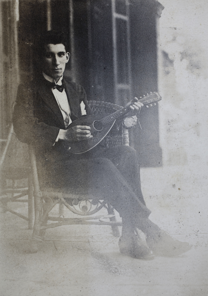 John Henderson sitting on a wicker chair holding a mandolin, Shanghai