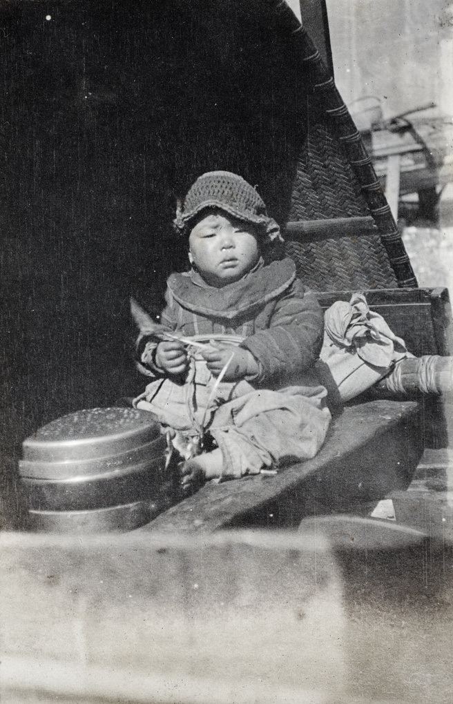 Boat-dwelling child wearing a crochet hat on a river boat, Shanghai