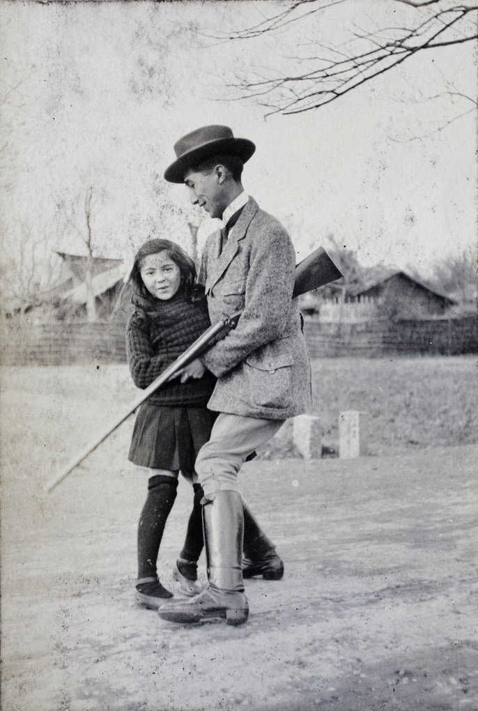 Tom Hutchinson with a hunting rifle under his arm and dancing with a young girl, Shanghai