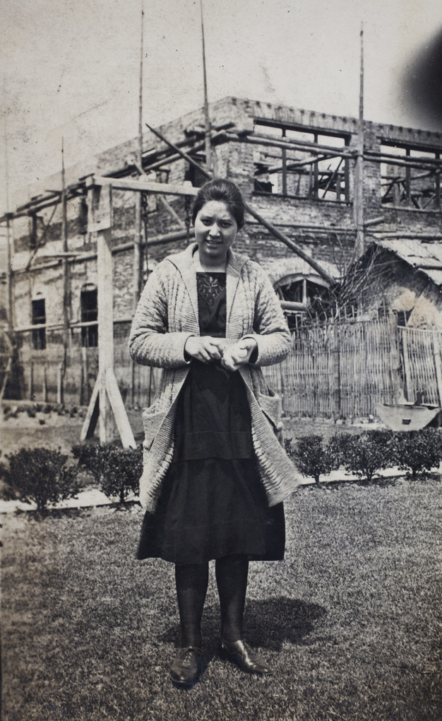 Sarah Hutchinson clutching a handful of eggs in the garden of 35 Tongshan Road, in front of a new house under construction, Hongkou, Shanghai