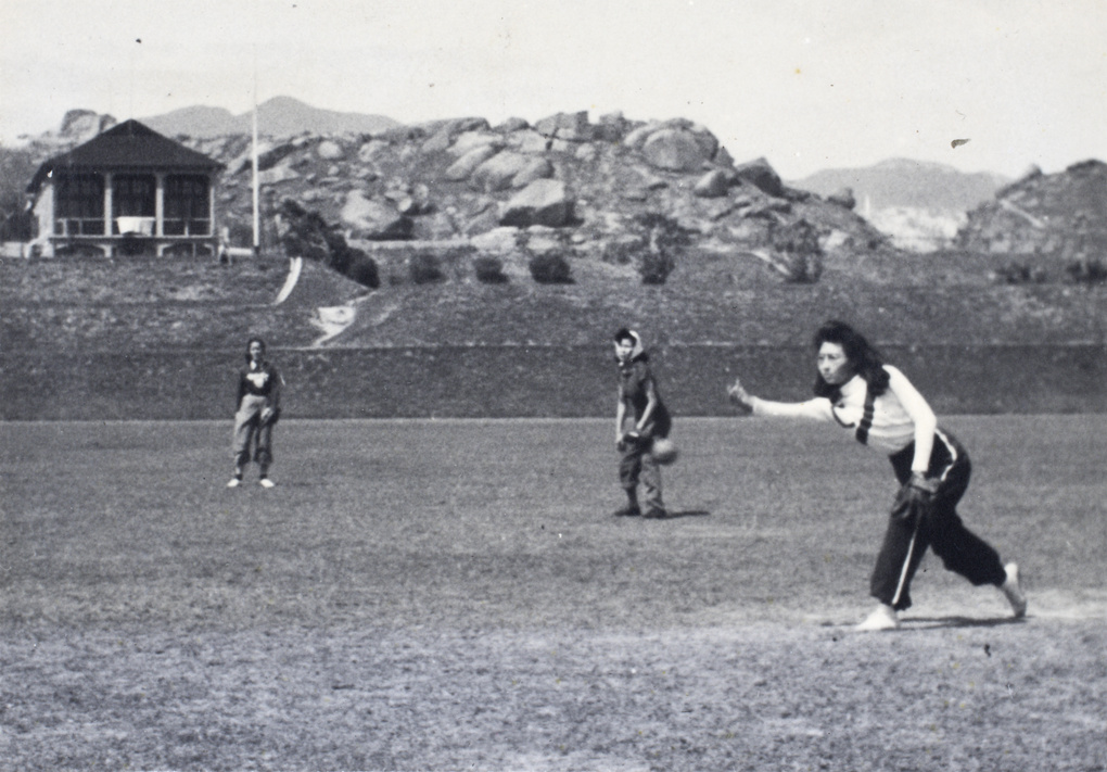 Gladys Hutchinson pitching a ball during a softball game, Kowloon, Hong Kong