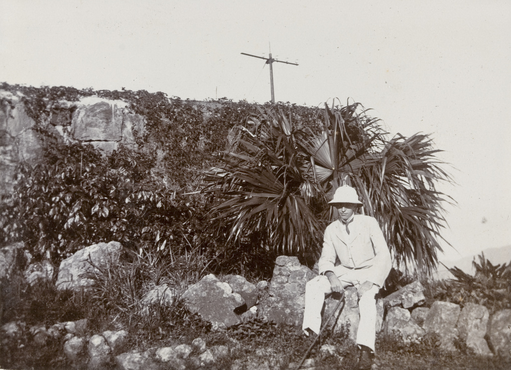 William Hoy sitting on some rocks by a palm tree