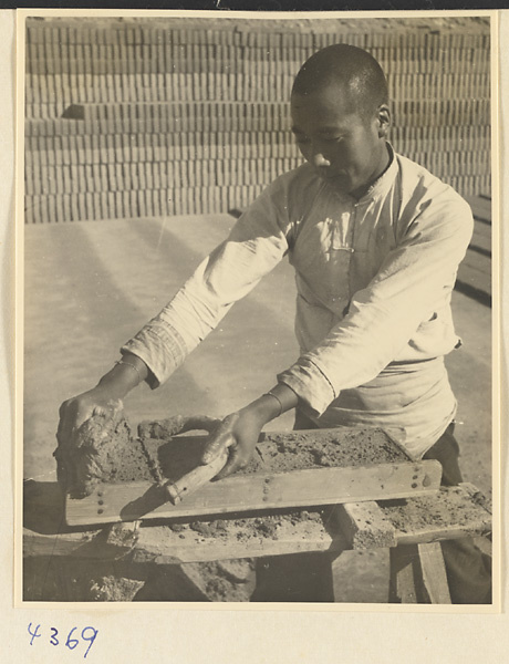 Man filling a mold with clay to make bricks at a brick factory near Baoding