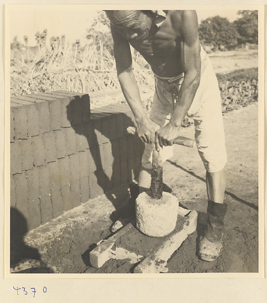 Man tamping down clay in a mold at a brick factory near Baoding