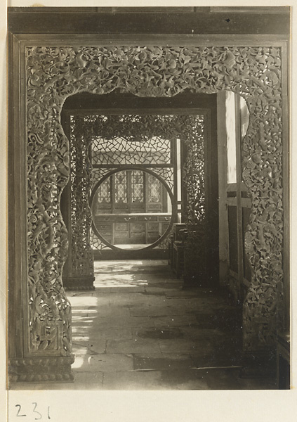 Building interior showing carved wooden doorways with relief work and latticework partition with moon gate and cracked-ice pattern at the New Wu Garden