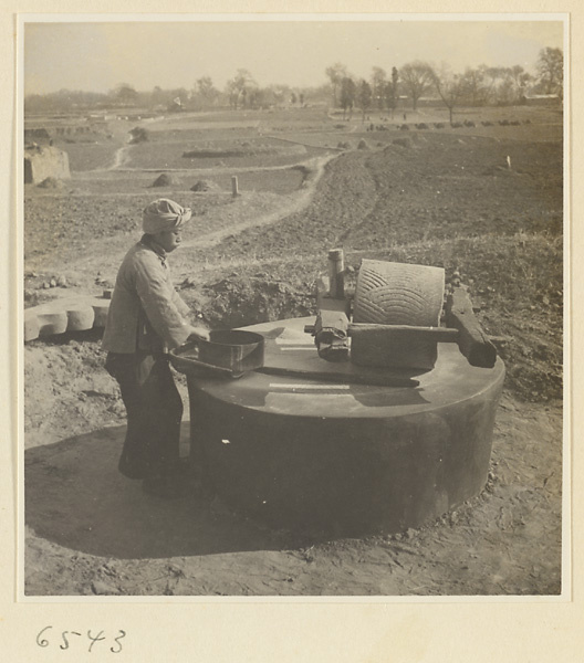 Man with baskets working at a grindstone