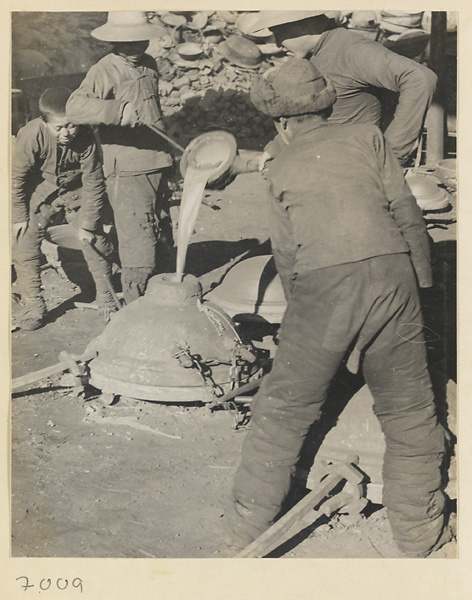 Men pouring molten iron into a mold at a foundry near Mentougou Qu