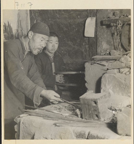 Blacksmith and assistant working at a forge