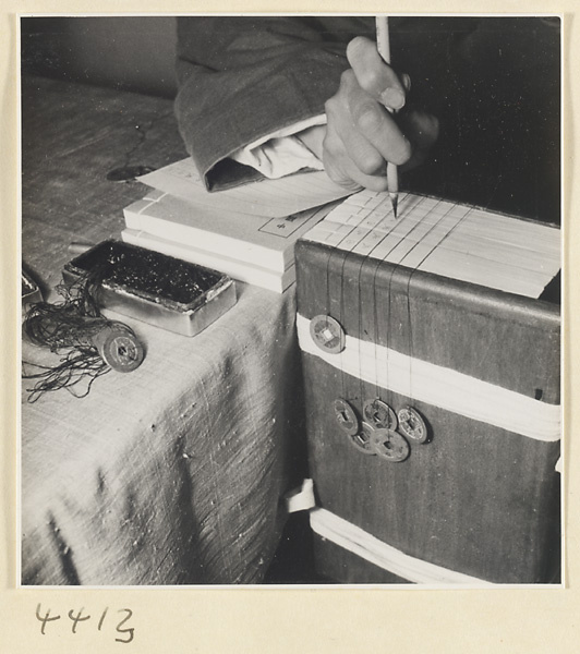 Man writing title and volume numbers on the heels of the fascicles of a multi-volume book