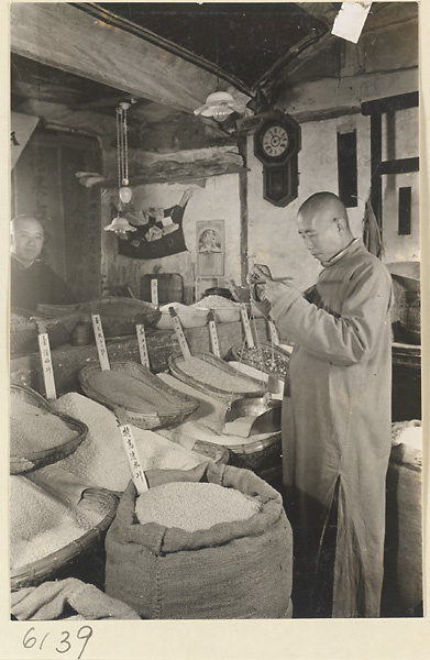Grain merchant measuring grain with a scale in his shop