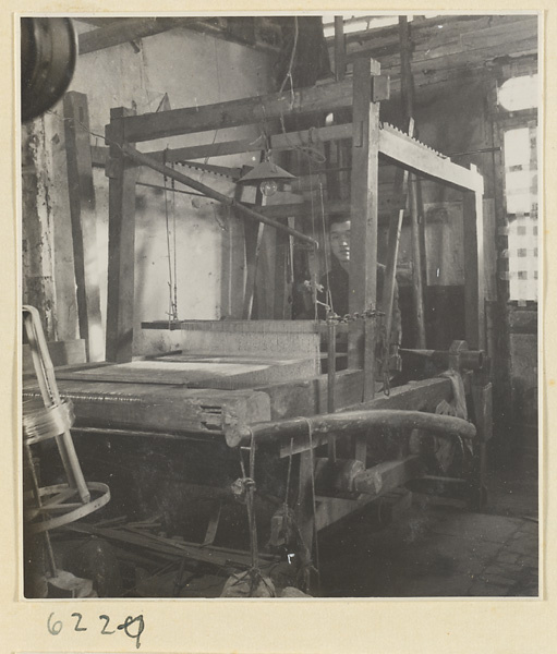 Interior of copper-net factory showing a man working at a loom