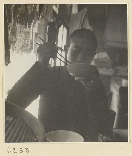 Interior of a scroll-mounting shop showing a man eating