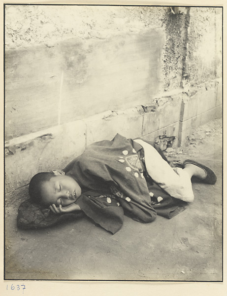 Boy wearing ceremonial costume sleeping in the street