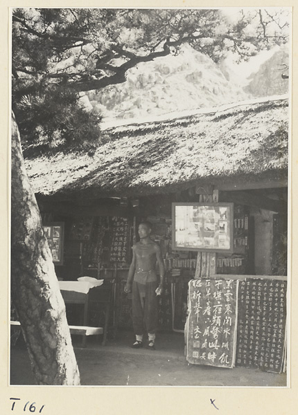 Man next to displays of photographs and inscriptions in front of building on Tai Mountain