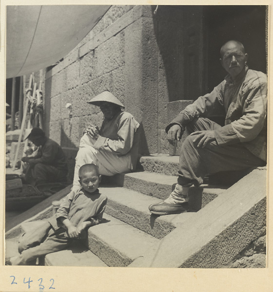 Men and boy sitting on steps in a fishing village on the Shandong coast