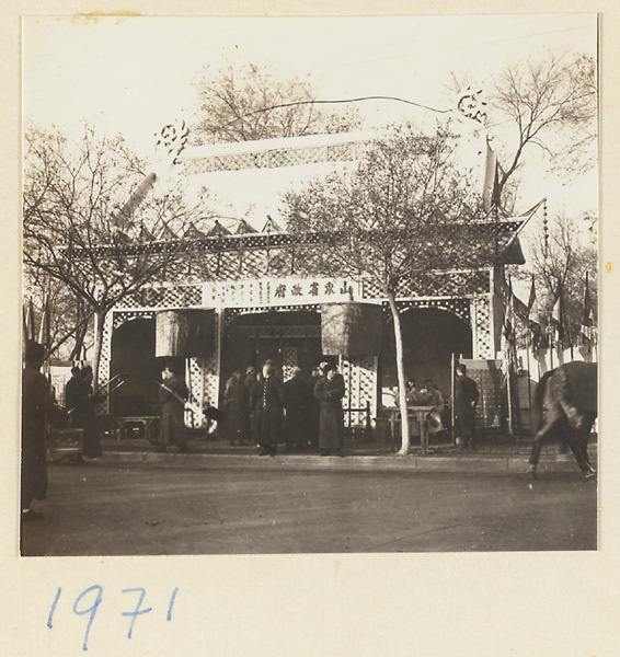Members of a funeral procession and umbrellas outside a paper pavilion erected for the funeral