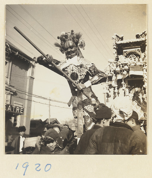 Paper figure armed with a trident and paper structure containing a portrait of the deceased being carried in a funeral procession