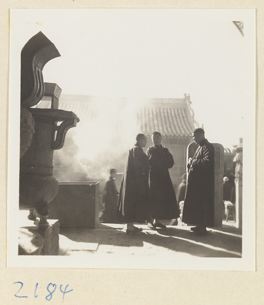 Men standing next to incense burners in smoky temple courtyard on Miaofeng Mountain