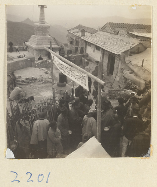 Pilgrims passing under an inscribed banner on the terrace next to the stupa-style pagoda on Miaofeng Mountain