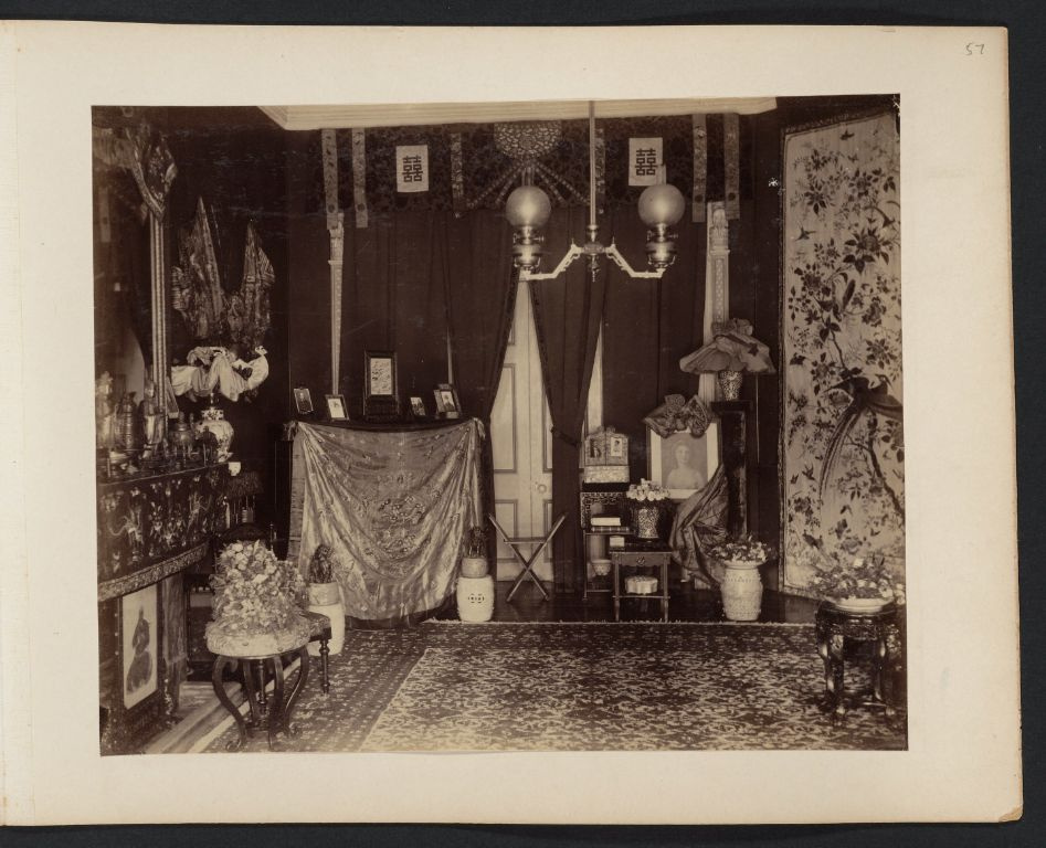 Room with photographs, Chinese art objects, and decorative silk hangings, Drew family home, Canton
