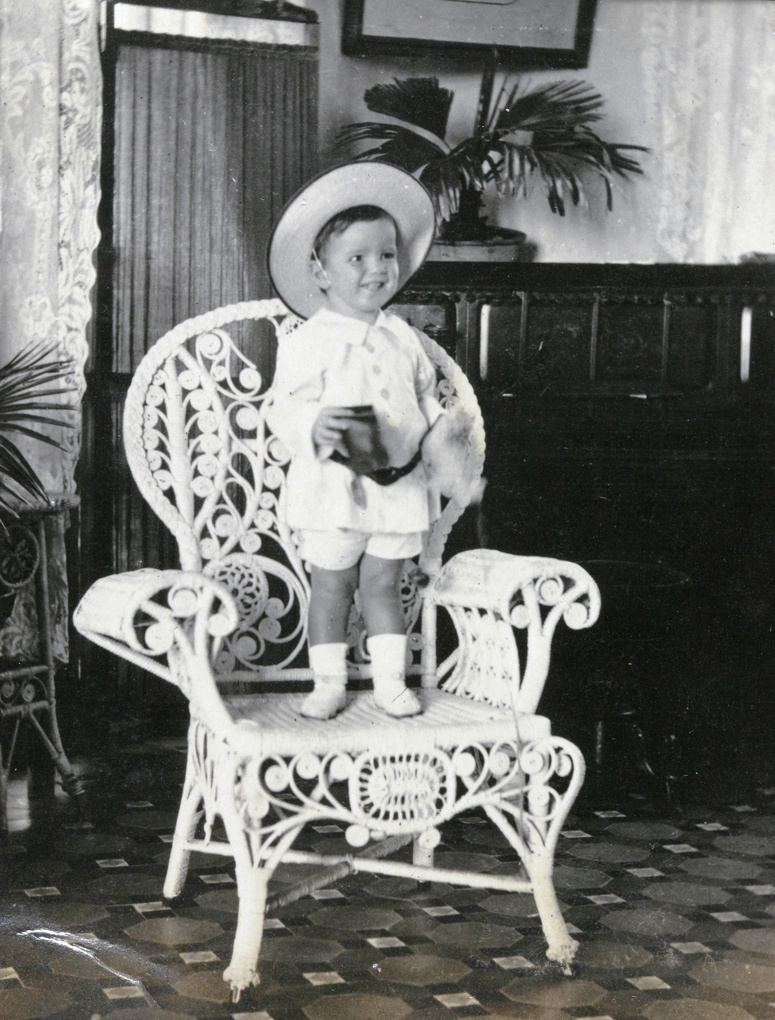 A boy standing on a rattan chair