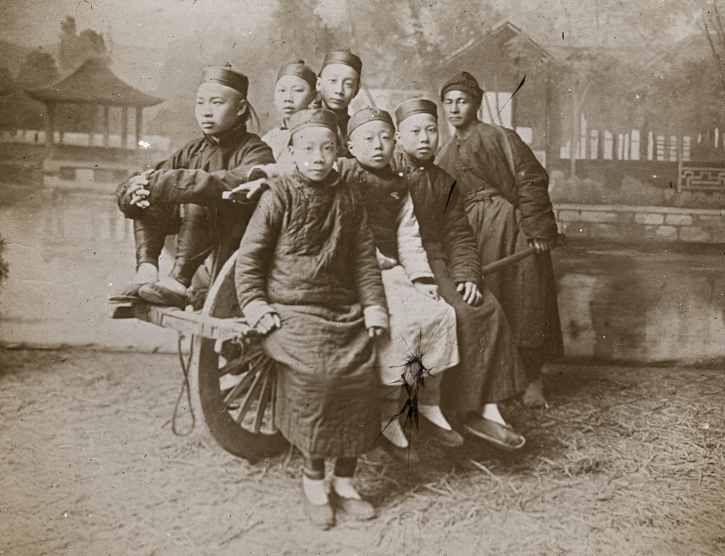 Studio portrait of six young men on a wheelbarrow