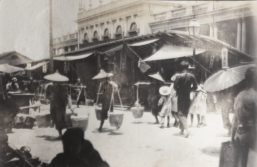 Porters carrying baskets, by a street market outside Queen's College, Hollywood Road, Hong Kong