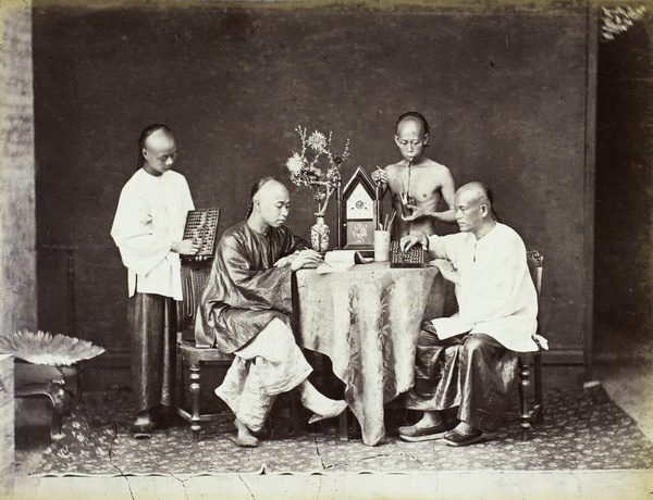 Studio photograph of four men writing, smoking opium and posing with abacus around the table, Hong Kong
