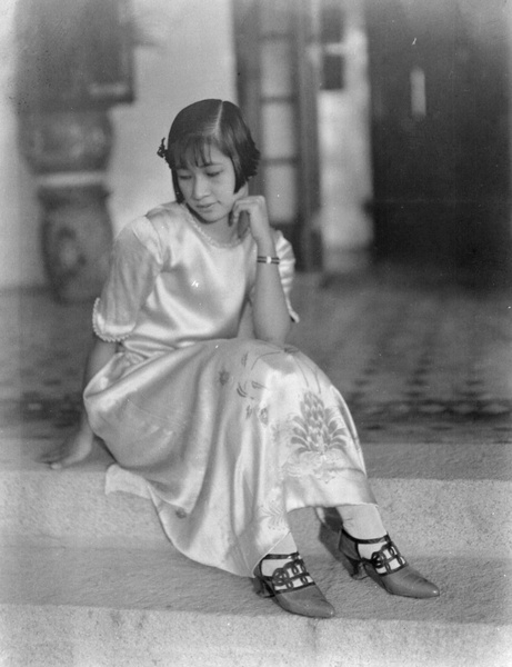 A woman posing in Western-style silk dress and high heels