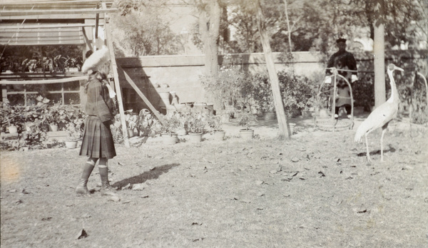 Gigi Detring in the Commissioner's garden, Tientsin, with a crane