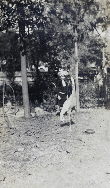 Gigi Detring in Commissioner's garden, Tientsin, with a crane