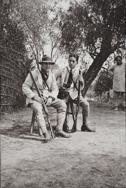 Charles Hutchinson and John Piry sitting on a trestle with hunting rifles, Shanghai