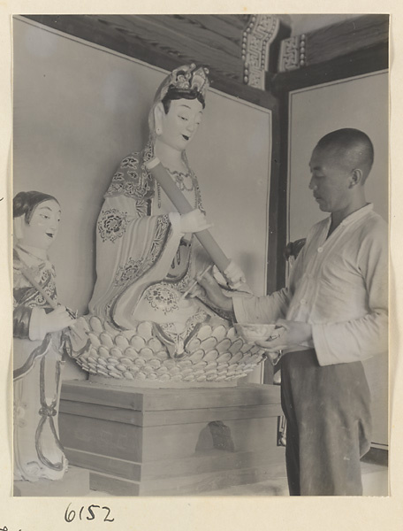 Monk applying paint to statue of a Bodhisattva at the Sheng mi zhi tang Monastery