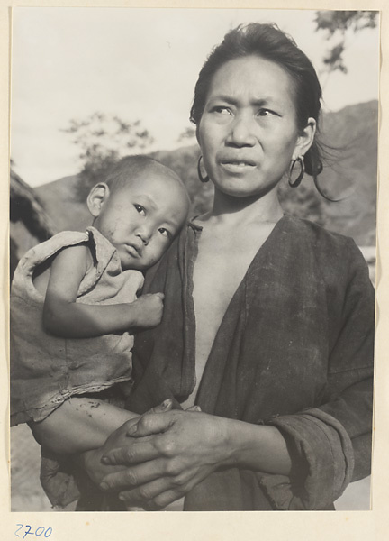 Woman wearing earrings and holding a child in the Jumahe Valley