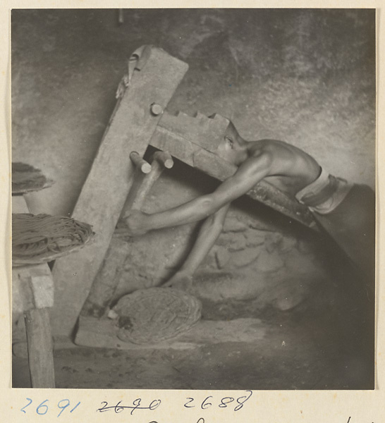 Man pressing wood pulp through a sieve at incense factory west of Ts'a-ho Village [sic] in the Lost Tribe country