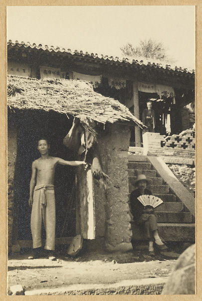 Three men in front of a temple hewn out of rock near the Guanyanling Pass