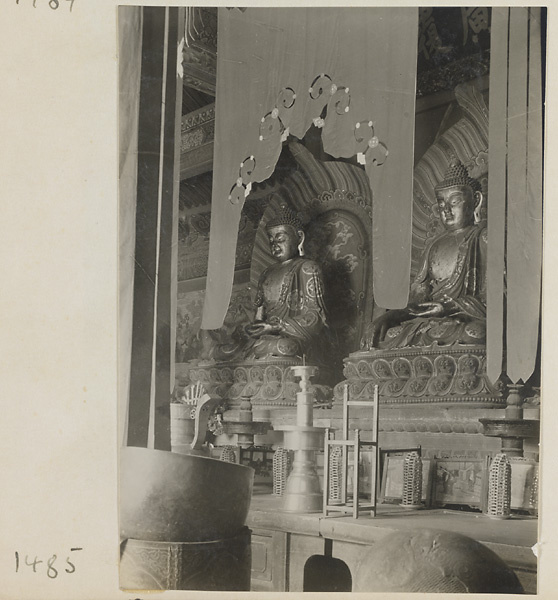 Temple interior showing altar with Buddha statues, ritual objects, and musical instruments at Qian men temple or Guan di miao