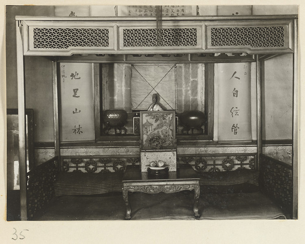 Altar with shrine figure, hanging scrolls, and panel with carved scene on top of a table at Xi yu si