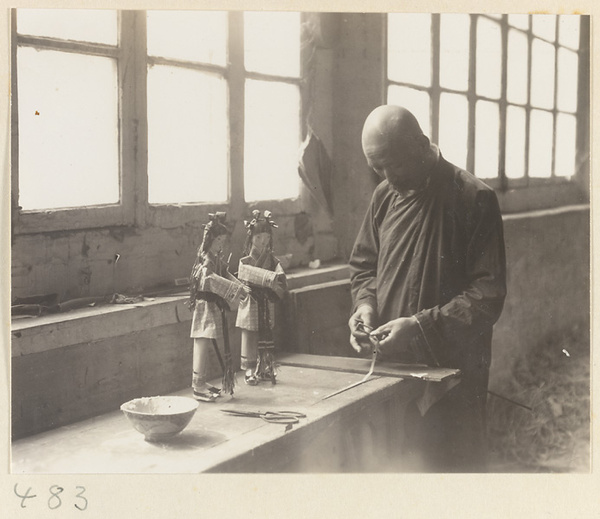 Temple interior showing a Buddhist monk making paper figures at Fa yuan si