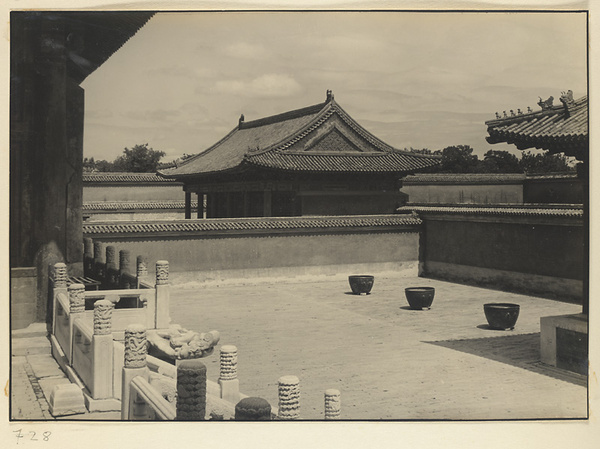 Marble balustrade and dragon-headed gargoyle on east terrace of Zhong dian, bronze water vats, and east side hall of Diao dian on far side of wall