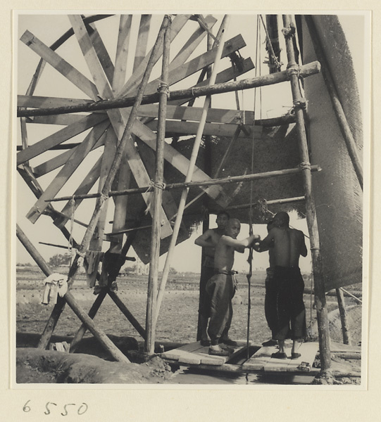 Men drawing water from a well to irrigate a field