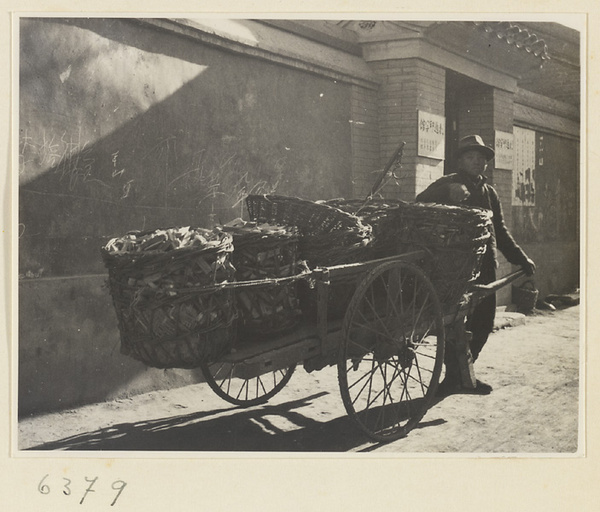 Itinerant charcoal seller with his cart loaded with baskets of charcoal