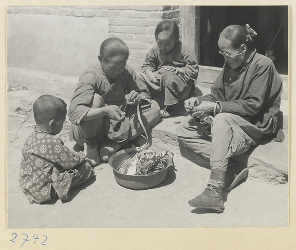 Children watching women with bound feet making souvenirs of braided colored straw at Bei'anhe