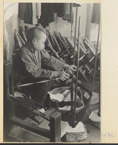 Boy winding thread onto reels for weaving